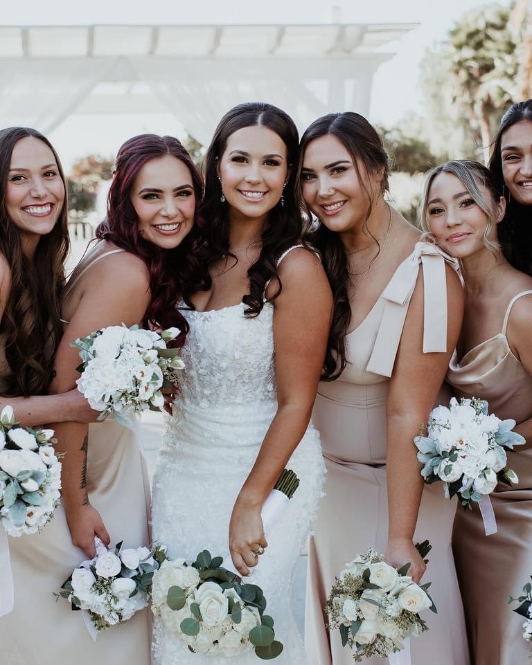 Bridal party and bride with styled hair and white floral bouquets