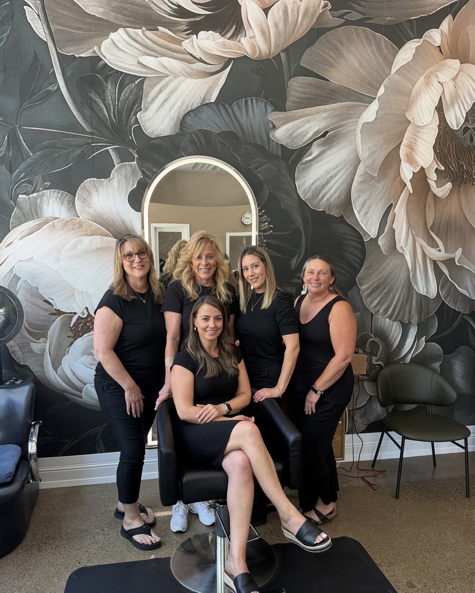 Timi Balla and styling team in front of the salon floral mural wall